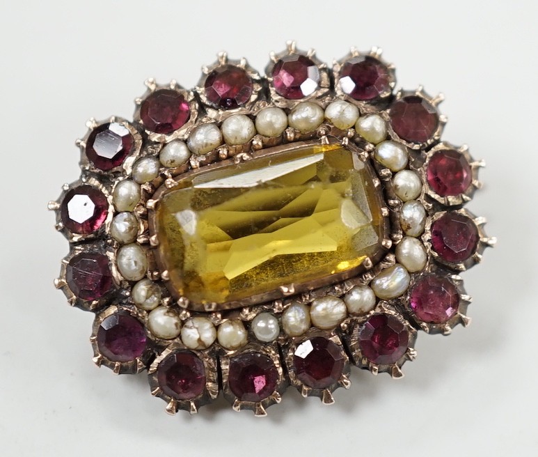 An early 19th century yellow metal, yellow paste, foil backed garnet and split pearl set oval brooch, 24mm.